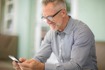 Mature handome man sitting outside reading his emails.