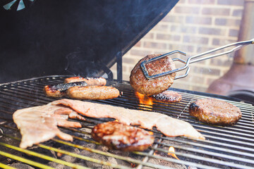 Summer time outdoor BBQ cooking meat with flames