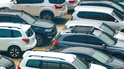 White and black car parked at concrete parking lot of shopping mall in holiday. Aerial view of outdoor car parking area of the mall. Automotive industry. Automobile parking space. Used car business.