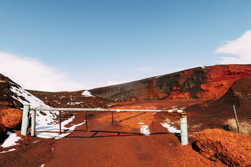 Martian landscapes in Iceland. The red crater of The Seydisholar volcano. The quarry of red soil mining. White snow lies on red soil, Closed gate at the entrance.