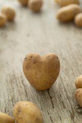 Kartoffel in Form eines Herzes aus frischer Ernte auf weißem Holzhintergrund