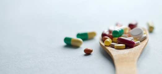 pharmaceutical medicine pills, tablets and capsules in a wooden spoon on a blue table. Medical and health concept. Close-up photography for your design