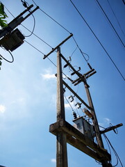 Obraz premium AC transformers and high voltage cables on the pole in the view below Three phase transformer for converting high voltage to low voltage On a bright sky background. Selective focus