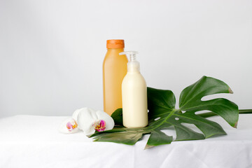 Cosmetic cream container and orchidea flowers and monstera leaf on white background