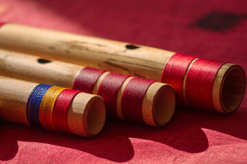 Close up of blowing hole of hindu bamboo flute called Bansuri on a red table.