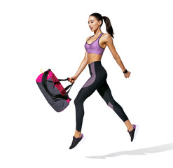 Go to training. Sporty girl with bag in motion. Photo of girl in fashionable sportswear on white...