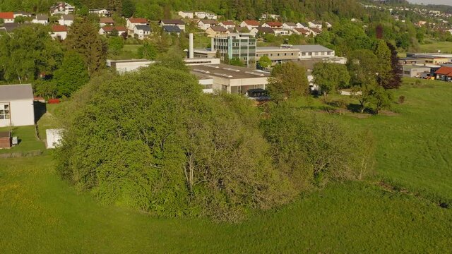Flying backwards with a drone focused from a green spring tree up to the cityscape of the recreation area of the Schwaebische Alb in germany