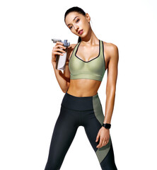 Resting time. Sweaty girl with opens bottle of water. Photo of girl with perfect body on white background. Strength and motivation