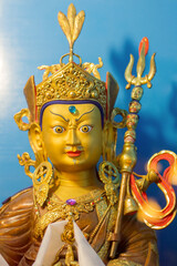 Vertical shot of gold statue of tibetan buddhist master Guru Rimpoche or Padmasambhava.