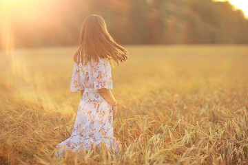 Fototapeta na wymiar young brunette in summer with long hair in a field, happy person health beauty posing at sunset