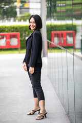 Fashion portrait of young beautiful woman sexy outdoor. black suit, standing on blur urban background.