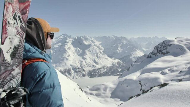 Splitboarder standing on top of a mountain in Switzerland and watching the view.