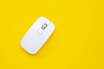 White computer mouse on yellow background.
