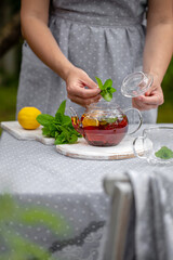 
woman brews black tea with lemon and mint
