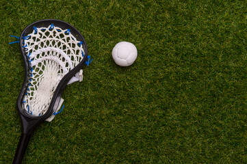 Lacrosse stick and white  ball on grass background. Team sport concept.