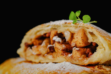 Apple strudel cut on a black background background blurred