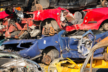 Broken cars in different colors on a scrap yard used for recycling 