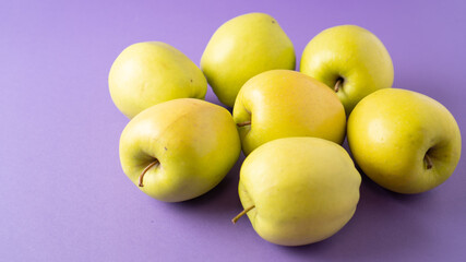 Yellow apples on violet background. Concept of healthy food for teeth. Bright juicy and ripe apples. Wallpaper
