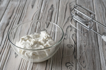  whipping cream using electric hand mixer on the gray rustic wooden table