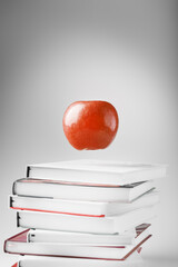 A red Apple hangs above the books on a white background.