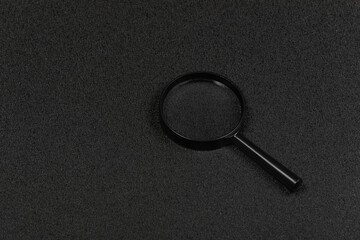 Black magnifying glass on black background. Magnifier. Search