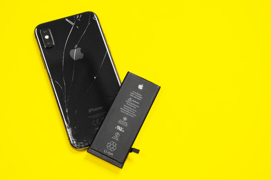 April 11, 2020, Rostov-on-Don, Russia:  Lithium ion black battery from Apple iPhone X and smartphone on a yellow background. Replacing the old damaged battery in your smartphone.