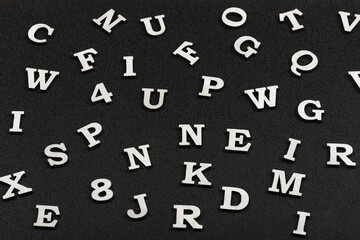 Letters of Latin alphabet on black background. Seamless black and white pattern of randomly placed letters