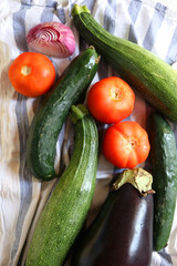 Homegrown summer vegetables on the kitchen counter: tomato, zucchini, cucumber, eggplant and purple onion. Top view.