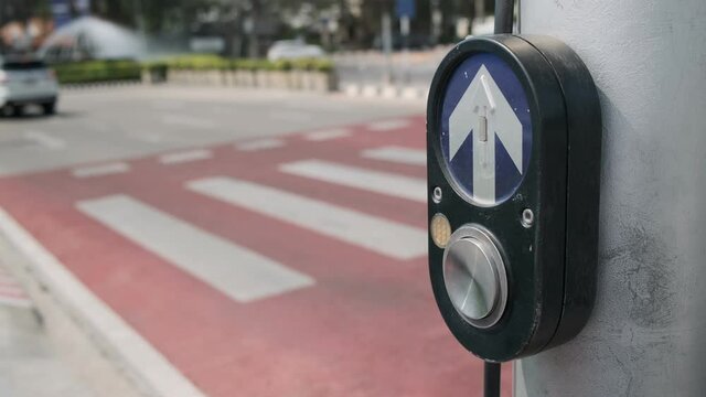 woman pedestrian presses finger on traffic signal switch button at crosswalk close-up.