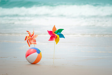 Obraz premium Colorful ball and paper windmill on sandy summer tropical beach with blue sea