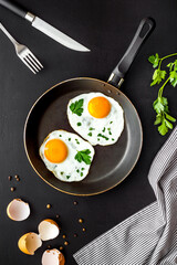 Fried eggs on frying pan on black desk top-down