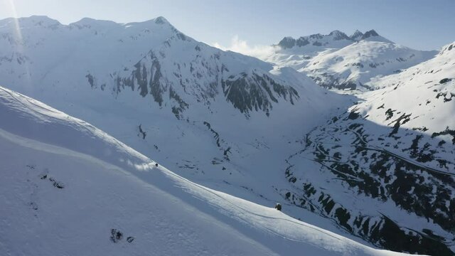 Aerial footage of a snowboarder riding down a mountain.
