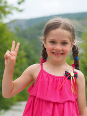 The little girl smiles and shows two fingers. The child shows a victory sign. The concept of success and development.