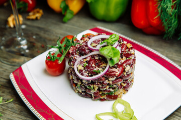 Restaurant dish on a wooden background with vegetables. Salad with beef tenderloin and arugula on a plate.