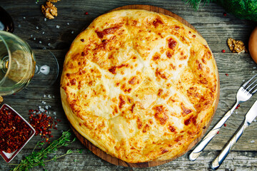  Azerbaijani restaurant dish with vegetable decor on a wooden background. Khachapuri in Megrelian on the Board.