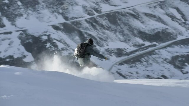 Snowboarder riding down the backcountry in Switzerland.