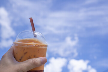 Plastic coffee mug in hand, the background is blue sky