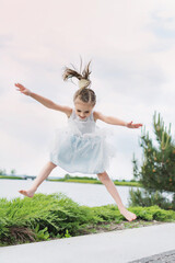 happy little girl on the beach. little girl in a white dress. little girl lying on the grass. little girl walking on the road