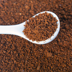 Background with fresh ground coffee in a white spoon