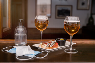 two glasses of beer and two medical protection masks on a bar counter during the new normal of covid 19