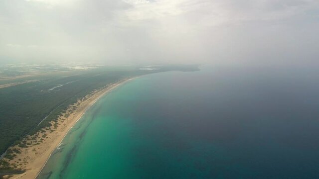 Establishing view of Kalogria beach, turquoise salt water ocean and seaside landscape on cloudy day, Greece, aerial 
