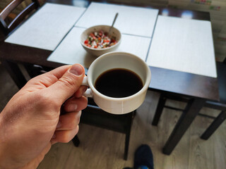 cup of coffee in a man hand in the kitchen