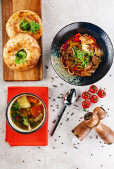 Lagman and shurpa served on the table with traditional bread, salt and pepper
