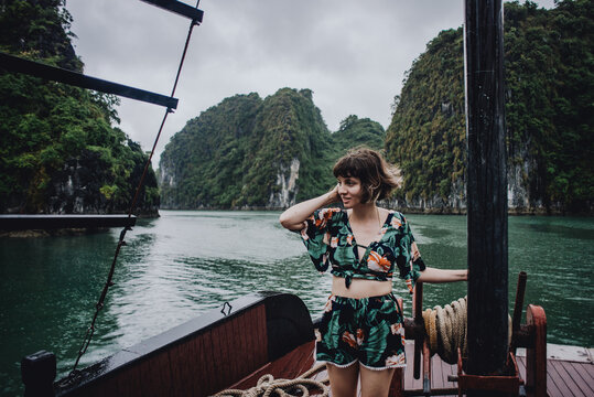 Young woman smiling in tropical clothes on a wooden boat in Halong bay Vietnam
