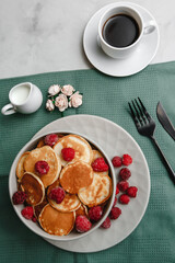 Trendy homemade Breakfast mini pancakes with raspberries and coffee on a white table. The view from the top. Side view. Space for text