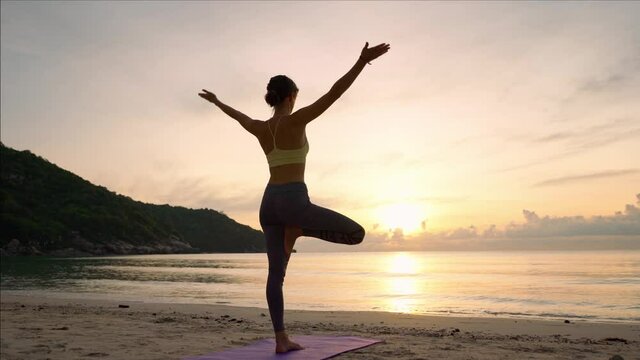 Doing yoga at sunrise, the girl practices the yoga tree pose, the harmony of the body with nature.