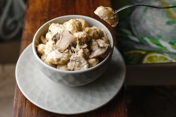 Potato gnocchi, Italian potato dumplings with cheese sauce, mushrooms and herbs on a plate. Side view, top view