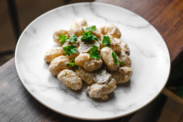 Potato gnocchi, Italian potato dumplings with cheese sauce, mushrooms and herbs on a plate. Side view, top view