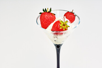 fragrant juicy strawberries in a glass with creamy ice cream with chocolate chips on a white plate, close-up