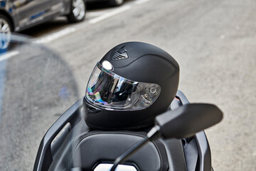 Fototapeta premium Moto scooter 125cc aparcada en la calle con casco 